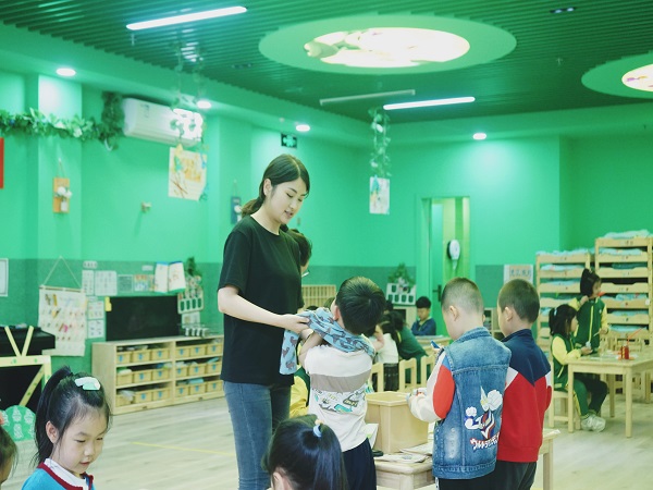 幼儿老师帮助幼儿穿衣。.jpg